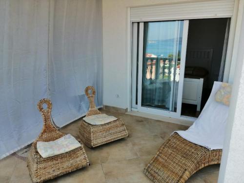 a living room with two wicker chairs and a balcony at Apartmani Jureta in Okrug Gornji