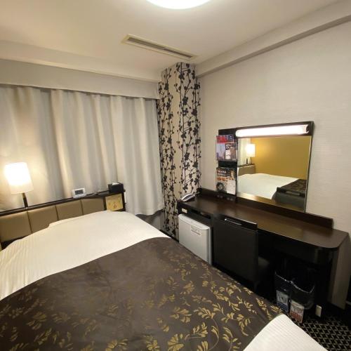 Habitación de hotel con cama y espejo en APA Hotel Toyohashi-Ekimae, en Toyohashi