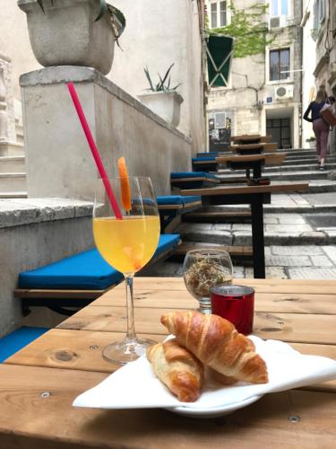 a table with a glass of orange juice and croissants at Slavija Culture Heritage Hotel in Split