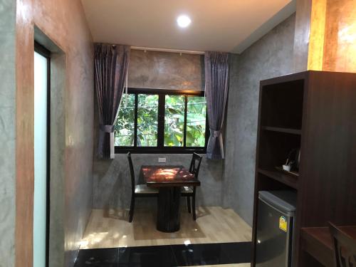ein Esszimmer mit einem Tisch und einem Fenster in der Unterkunft Nao Ta Chuang in Thung Song