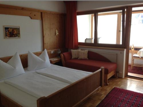 a hotel room with a bed and a couch and windows at Landhaus Appartement Kofler Ferienwohnungen,Zimmer in Maurach