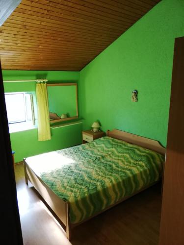 a green bedroom with a bed and a window at Apartments Edi Pogana in Punta Križa
