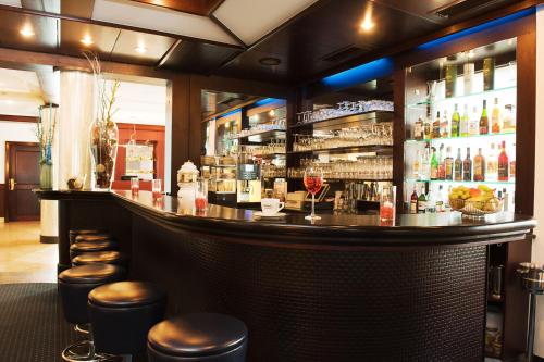 a bar in a restaurant with stools at Atrium im Park Hotel Regensburg in Regensburg