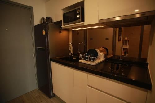 a kitchen with a sink and a black refrigerator at HuaHin DusitD2 Residences, apartments near beach in Hua Hin