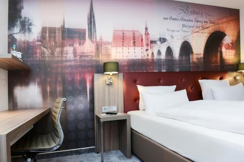 una camera d'albergo con letto, scrivania di ACHAT Hotel Regensburg im Park a Ratisbona