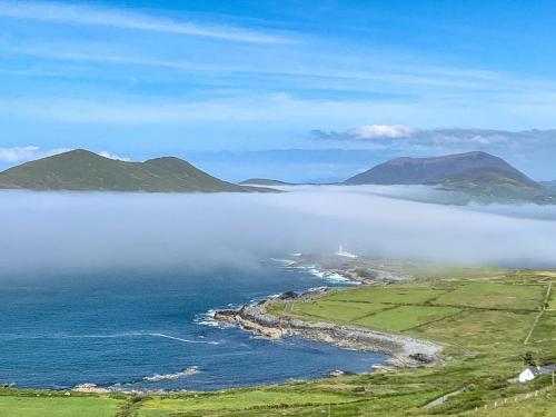 an island in the ocean with clouds in the water at Skellig Port Accommodation - 1 Studio Bed Apartment in Portmagee