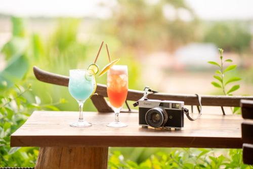 two glasses and a camera on a table with drinks at The Nature & Villas in Siem Reap