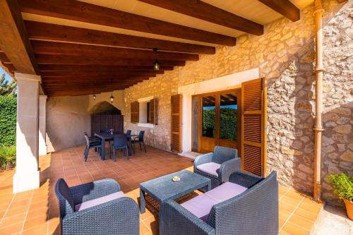 a patio with chairs and a table and a stone wall at Cas Batlet Antonia in S'Horta