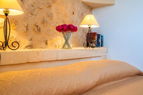 a bedroom with two lamps and a vase of red flowers at Cas Batlet Antonia in S'Horta