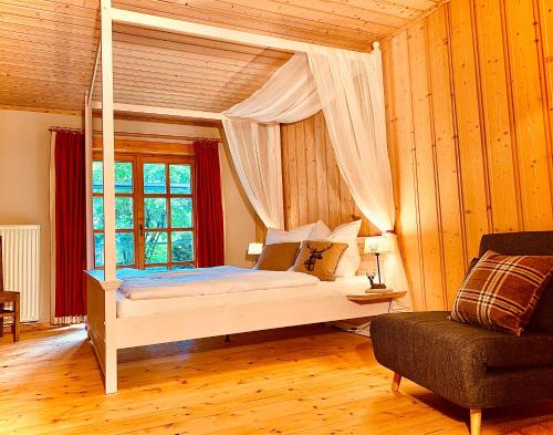 a bedroom with a canopy bed and a chair at Chalet Zugspitze in Grainau