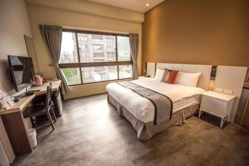 a bedroom with a bed and a desk and a window at Ruo Shui Hotspring Hotel in Jiaoxi