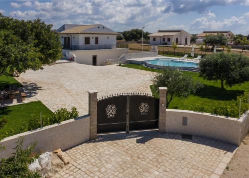 ein Tor in einer Einfahrt mit einem Pool und einem Haus in der Unterkunft Casa vacanze IL MANDORLO in Scicli