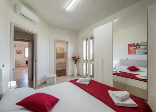 a white bedroom with a large bed with red pillows at Casa vacanze IL MANDORLO in Scicli
