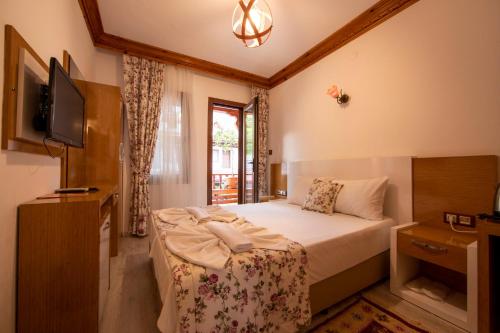 a small bedroom with a bed and a television at MANDALİN AKYAKA in Akyaka