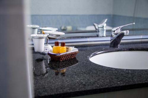 奇維塔卡斯泰拉納的住宿－艾爾德羅酒店，一个带水槽的浴室台面和一篮子的瓶子