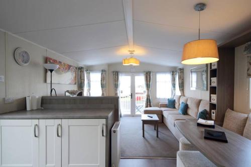 eine Küche und ein Wohnzimmer mit einem Sofa und einem Tisch in der Unterkunft Edinburgh - Seton Sands-Cameo Caravan-Pet Friendly in Edinburgh