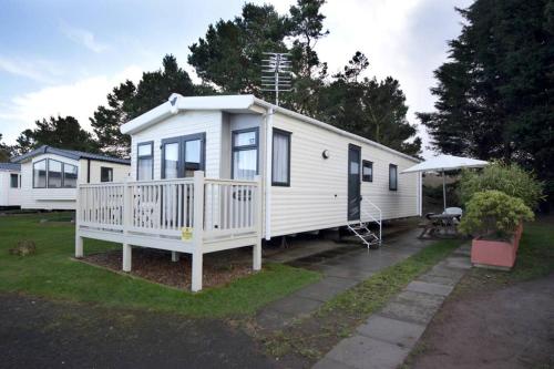 a white mobile home with a porch and a patio at Edinburgh - Seton Sands-Cameo Caravan-Pet Friendly in Edinburgh