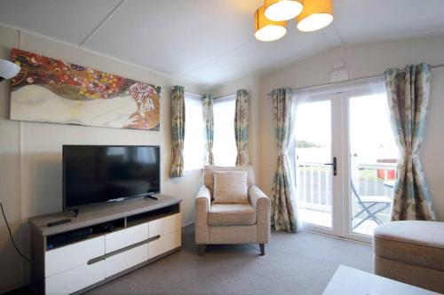 a living room with a television and a chair at Edinburgh - Seton Sands-Cameo Caravan-Pet Friendly in Edinburgh