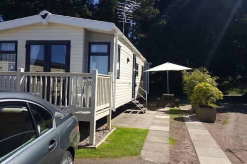 a small white house with an umbrella and a car at Edinburgh - Seton Sands-Cameo Caravan-Pet Friendly in Edinburgh
