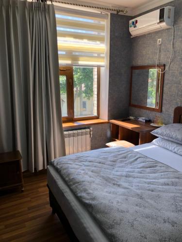 a bedroom with a bed and a desk and a window at Cinzano Complex in Samarkand