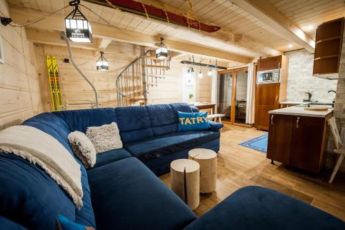 a living room with a blue couch and a kitchen at Domki Narciarskie Zakopane in Zakopane
