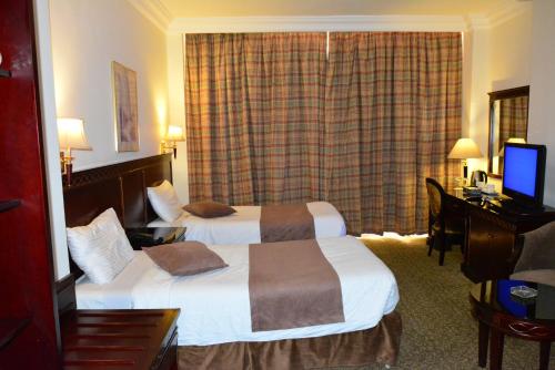 a hotel room with two beds and a desk at Rakeen Hotel in Amman