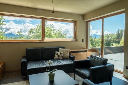a living room with a couch and chairs and windows at Haus Lichtenstern in Soprabolzano