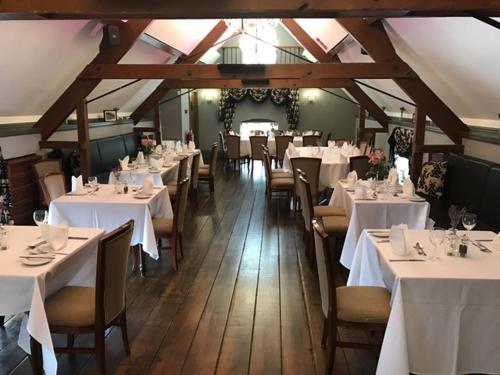 ein Esszimmer mit weißen Tischen und Stühlen in der Unterkunft The Barns Hotel in Cannock