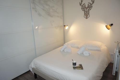 une chambre avec un lit blanc avec des serviettes dessus dans l'établissement L'Eucalyptus, charmant T2 au cœur du centre ville, à Rennes