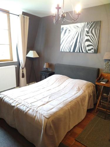 a bedroom with a bed with a zebra painting on the wall at Hotel La Croix De Vernuche in Varennes Vauzelles
