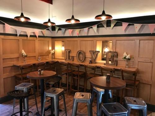 a restaurant with tables and stools in a room at The Barns Hotel in Cannock
