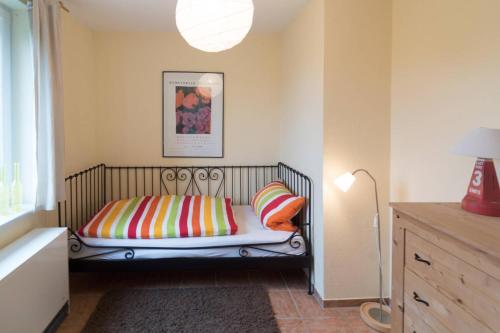 a bedroom with a bed with colorful pillows and a lamp at Ferienhaus Bettina in Dornumersiel