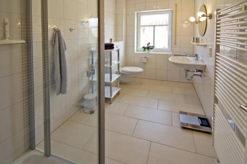 een badkamer met 2 toiletten, een wastafel en een douche bij Ferienwohnung Annegret in Dornumersiel