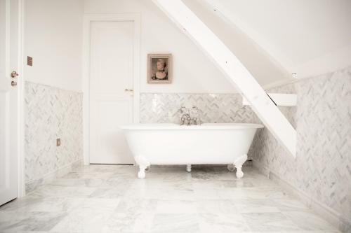 a white bathroom with a bath tub in a attic at Le 25bis by Leclerc Briant in Épernay