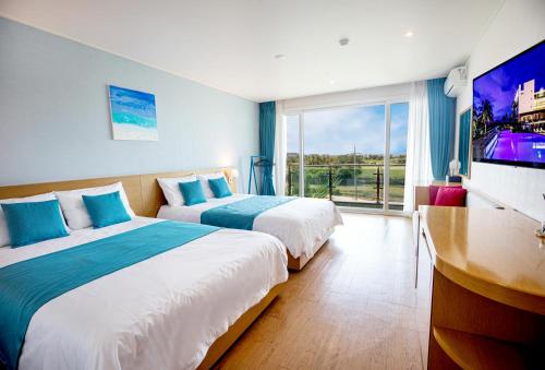two beds in a hotel room with a tv at The Four Grace Resort in Seogwipo