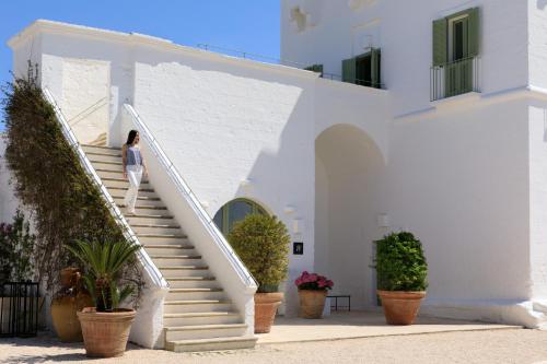 a woman walking up the stairs of a white building at Rocco Forte Masseria Torre Maizza in Savelletri di Fasano