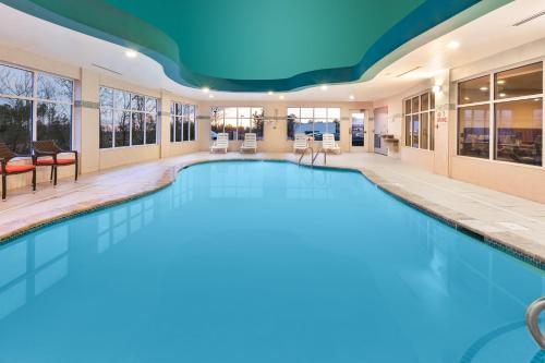 a pool in a hotel room with a large swimming pool at Holiday Inn Express & Suites Southport - Oak Island Area, an IHG Hotel in Oak Island