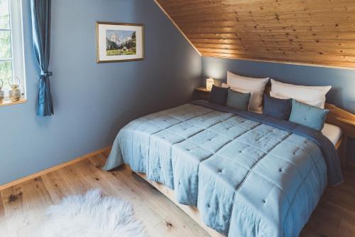 Schlafzimmer mit blauem Bett und Holzdecke in der Unterkunft Luxus Ferienhaus Altaussee in Puchen