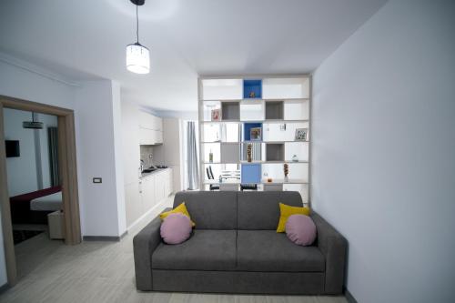 un soggiorno con divano grigio e cuscini gialli e rosa di Apartament Alegria by Alz a Mamaia Nord - Năvodari
