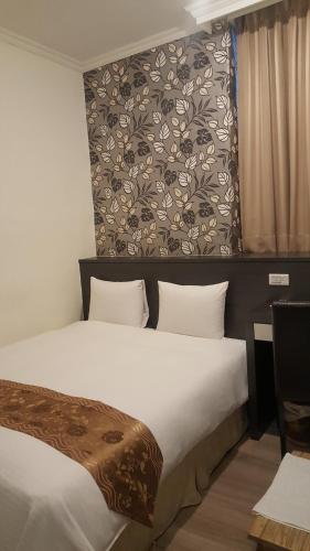a hotel room with a bed and a wall at Queens Hotel in Taipei