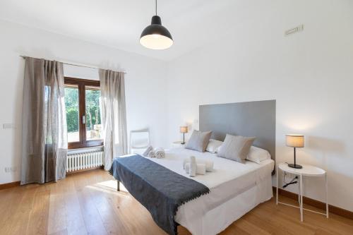 a white bedroom with a large bed and a window at Villa Piscina “La Trinità “ in Corciano