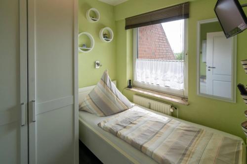 łóżko w pokoju z oknem w obiekcie Ferienwohnung Utkiek w mieście Dornumersiel
