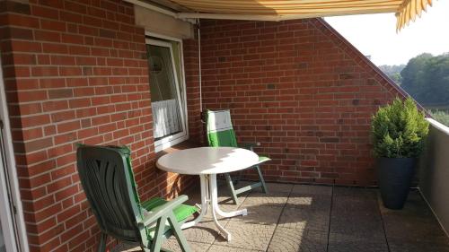 a table and chairs on a porch with a brick wall at Ferienwohnung Utkiek in Dornumersiel