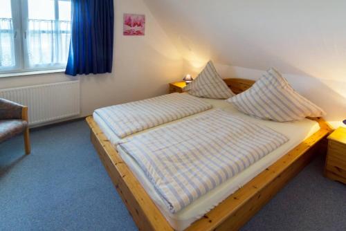 1 dormitorio con cama de madera y almohadas en Ferienwohnung Regina, en Dornum