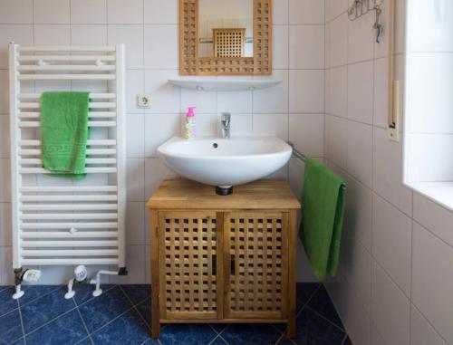 a bathroom with a white sink and green towels at Ferienhaus Strandruhe in Dornumersiel