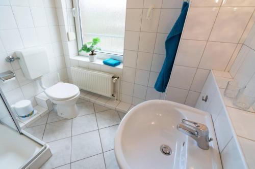 ein weißes Bad mit einem Waschbecken und einem WC in der Unterkunft Ferienhaus Sieleck in Dornumersiel