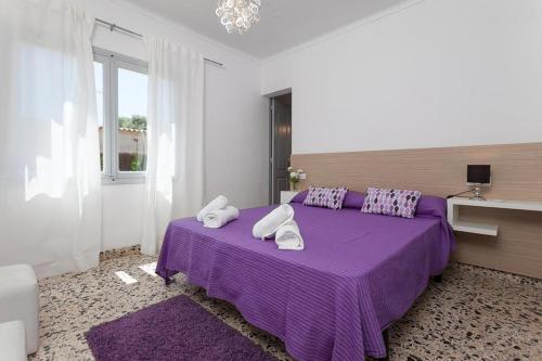 a bedroom with a purple bed with towels on it at Villa Rosales in Alcudia