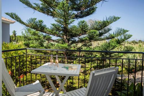 a table and two chairs on a balcony with a tree at ASTRA Village Resort in Svoronata
