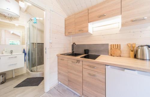 a kitchen with wooden cabinets and a sink at Domki nad morzem WOJTAS in Wrzosowo