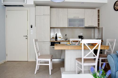 a kitchen with white cabinets and a table and chairs at Ralux apartman Tivat in Tivat